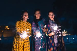 Three young Indian women with bengal fireworks, celebrating Indi